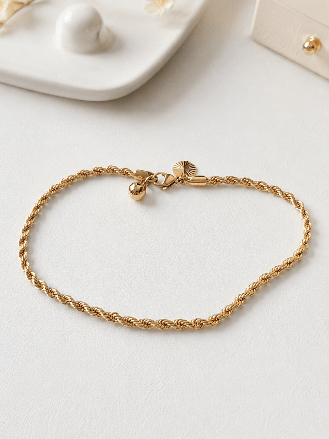 Gold-plated braided anklet on a light background