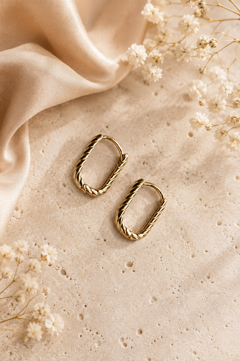 18k gold-plated twisted design oval hoop earrings on a light background