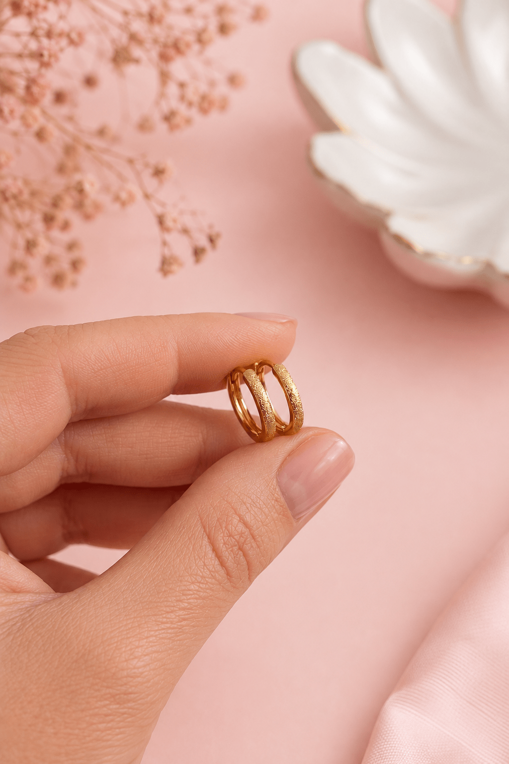 Small gold-plated textured hoop earrings in hand
