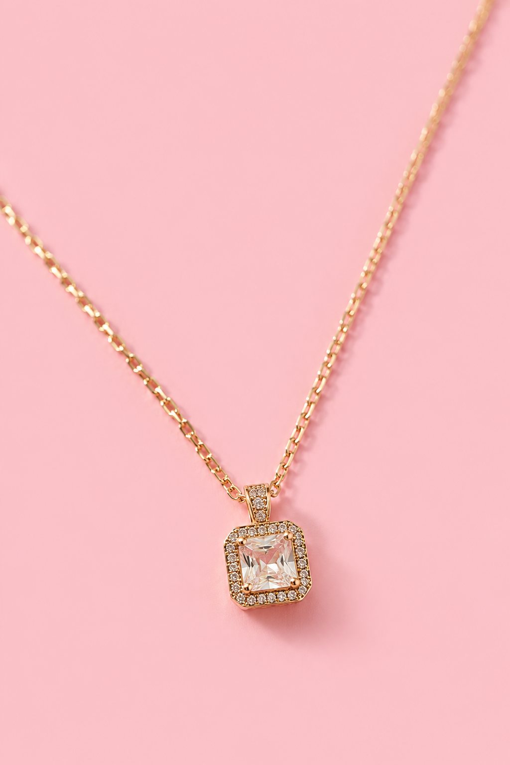 18k gold-plated necklace with a square pendant and clear zircons on a pink background