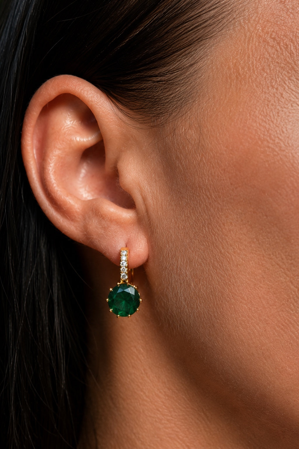 18k gold plated earrings with green cubic zirconia close up on the ear