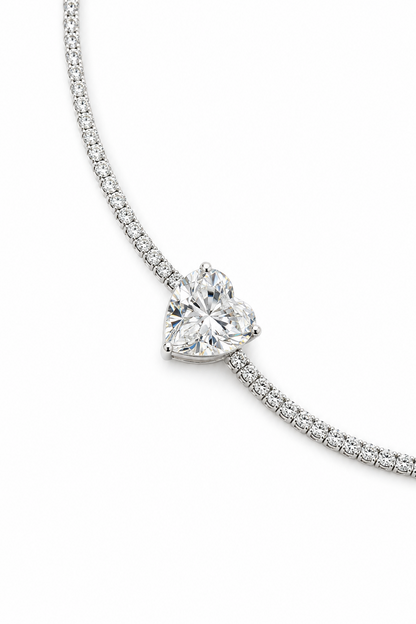 A close-up of a silver-plated bracelet with a heart-shaped crystal