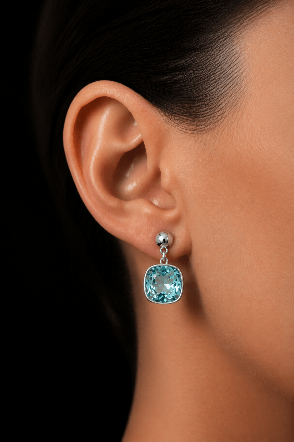 Close-up of silver plated earrings with aquamarine blue crystal