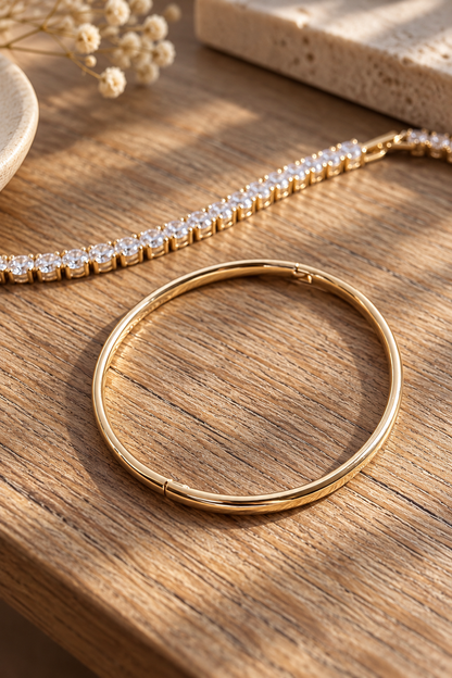 Apzeltīta bangle rokassprādze kopā ar tenisa rokassprādzi saules gaismā