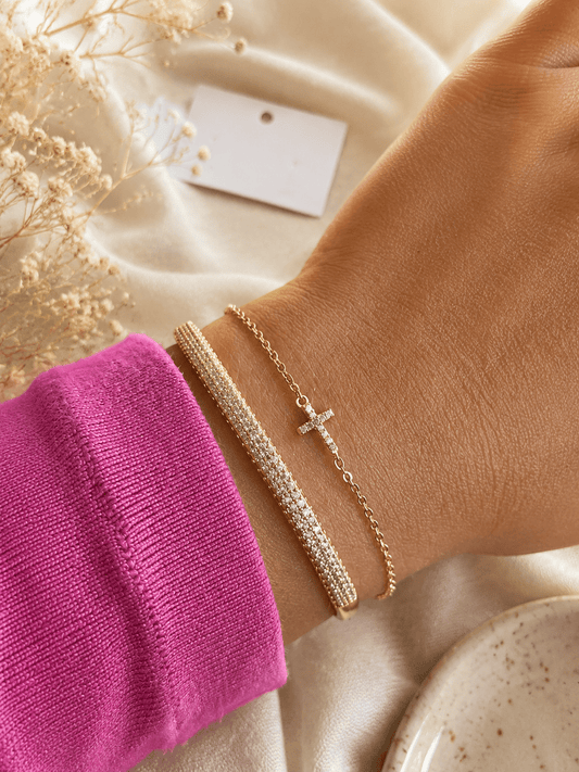 Gold plated bangle bracelet paired with delicate cross bracelet