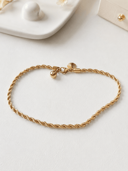 Gold-plated braided anklet on a light background