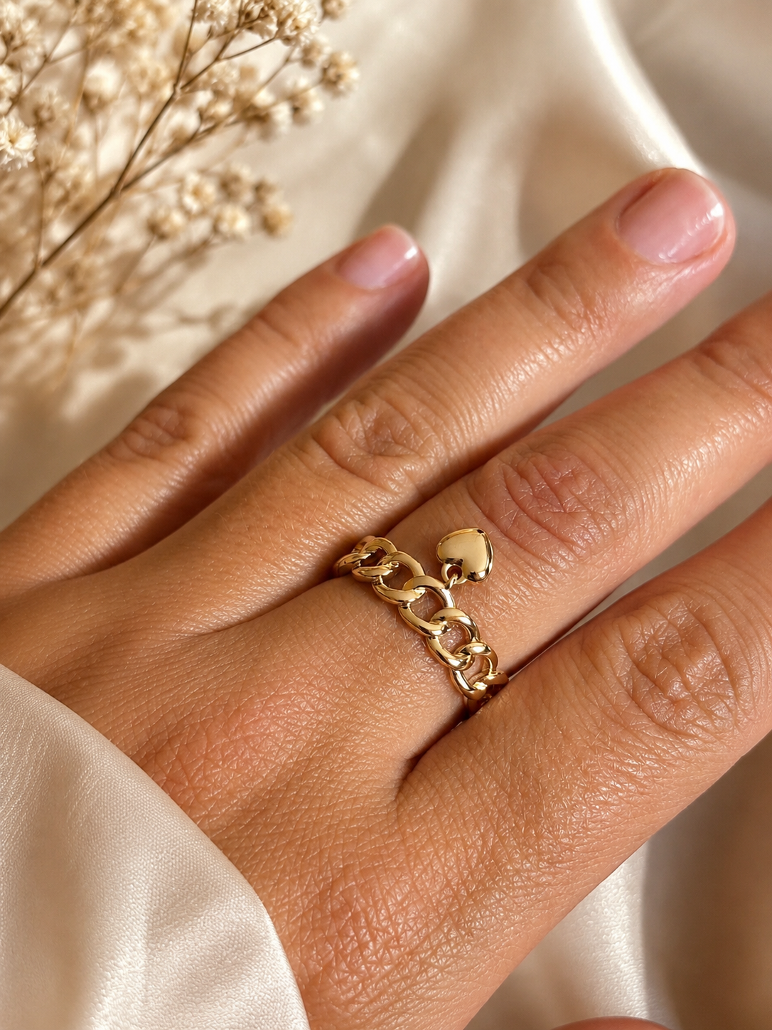 Chain ring with heart charm close-up on hand