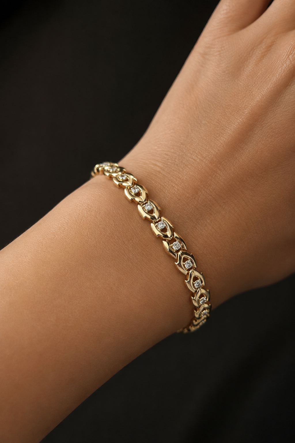 18k gold-plated bracelet with zircons on the hand on a dark background