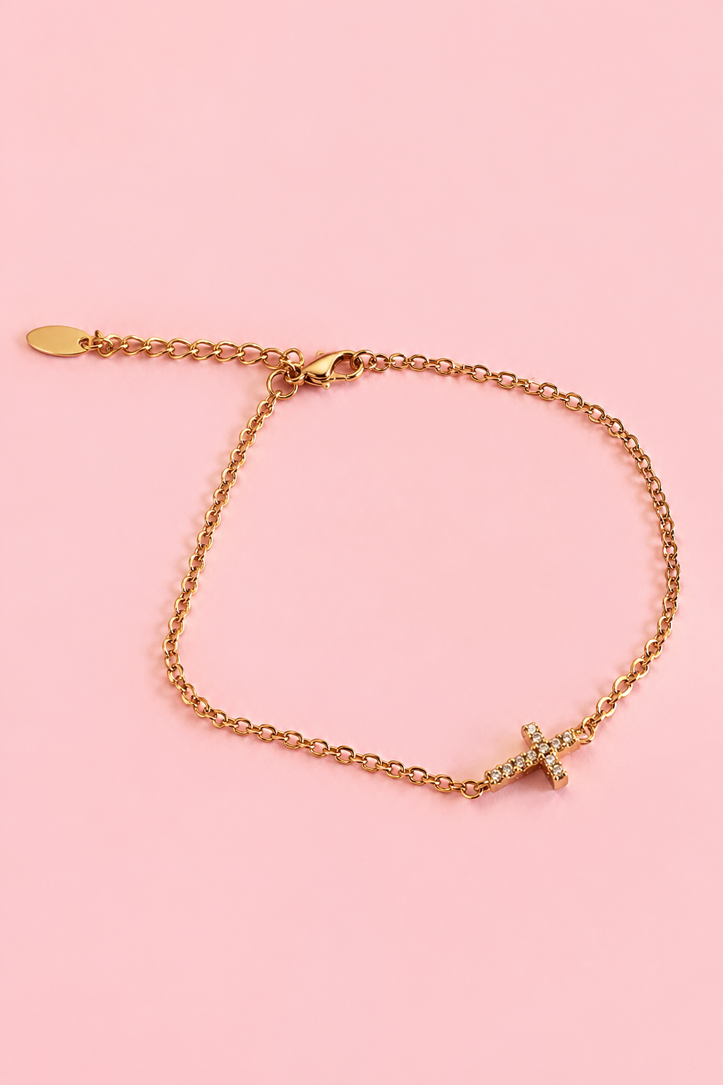 18k gold-plated bracelet with a zircon cross on a pink background