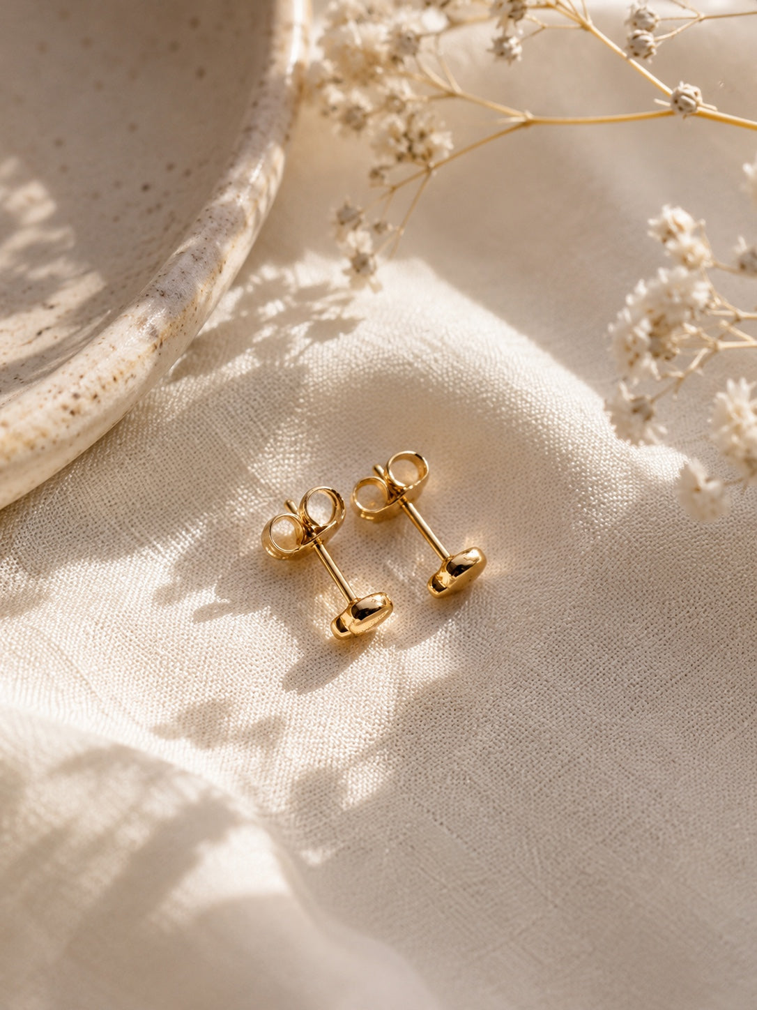 Liva 18k gold-plated heart-shaped stud earrings 5 mm on light fabric