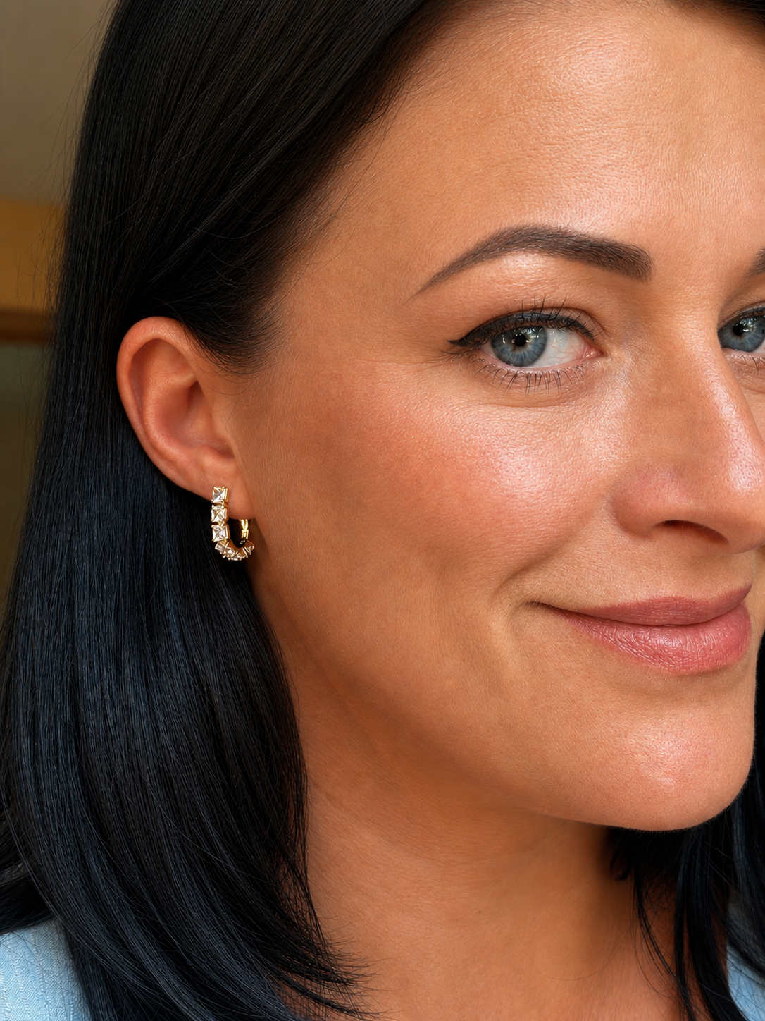 The woman wears Mirdza 18k gold-plated earrings with square cubic zirconias