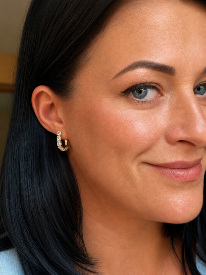 The woman wears Mirdza 18k gold-plated earrings with square cubic zirconias