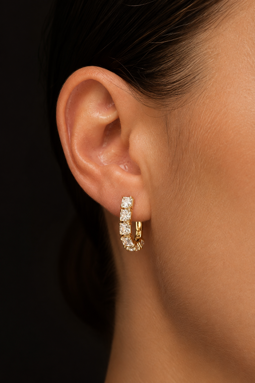 Sparkling 18k gold-plated earrings with square cubic zirconias on the ear close-up