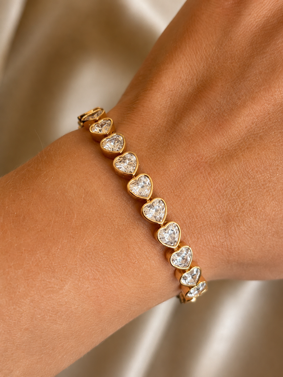 Close-up of gold-plated bracelet with crystal hearts on hand