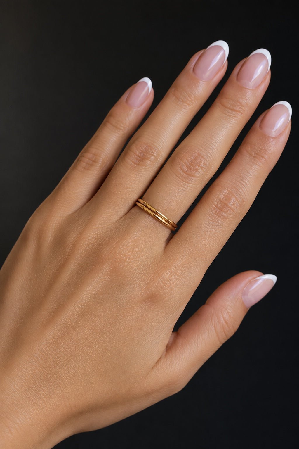 Fine 18k gold-plated ring on the hand on a dark background